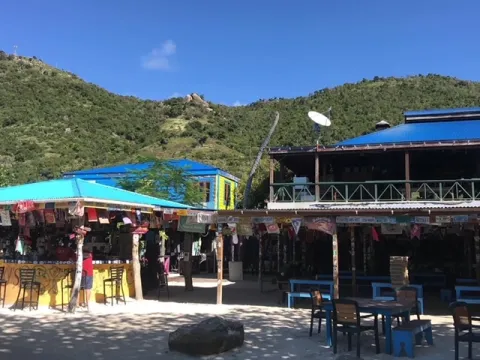 a group of people sitting at a table with a blue umbrella