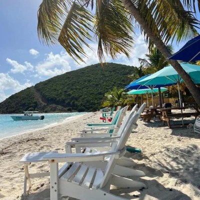 a group of lawn chairs sitting on top of a sandy beach