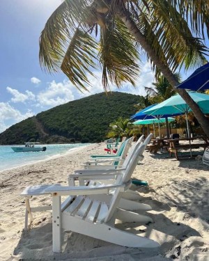 a group of lawn chairs sitting on top of a sandy beach