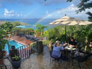 a group of people sitting at a table with a blue umbrella