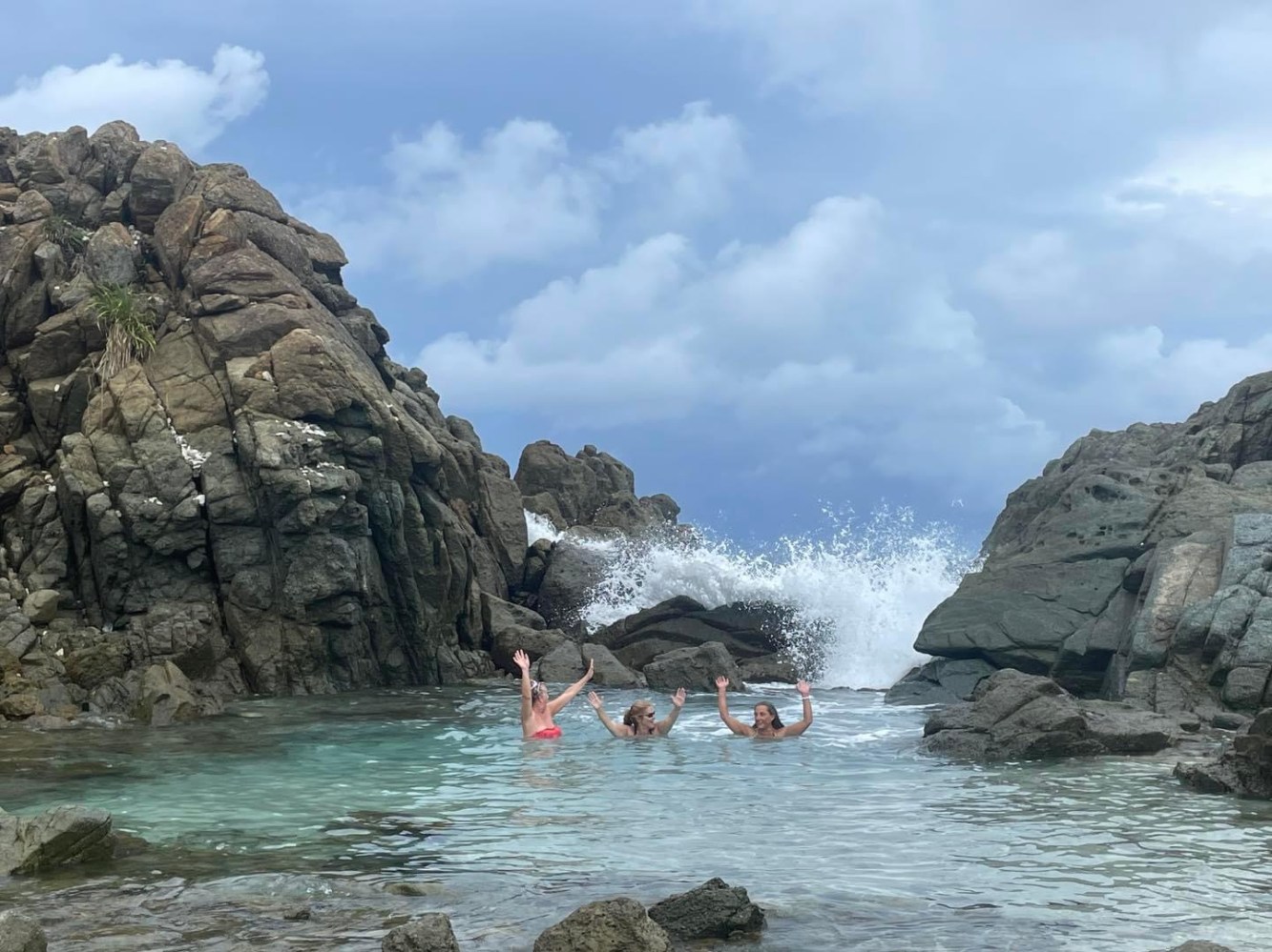 a group of people on a rock next to a body of water